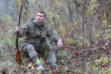 Man in camouflage and with guns in a forest belt on a spring hun