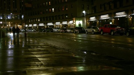 People walking on the sidewalk at night in urban rainy city