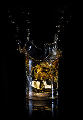 Splash from an ice cube in glass of whiskey
