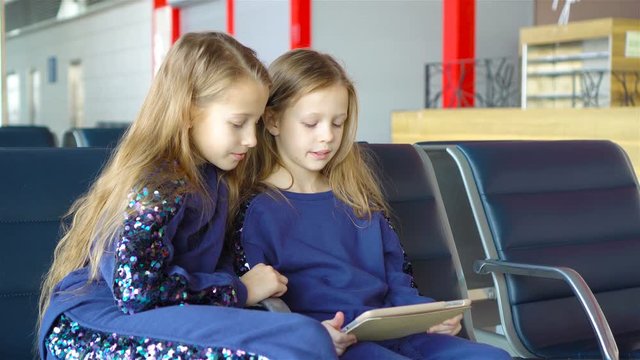 Little adorable girls in airport waiting for boarding playing with laptop