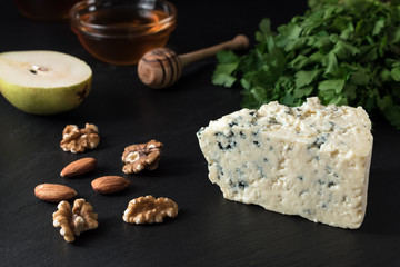 Tasty blue cheese with nuts and herbs on black stone board