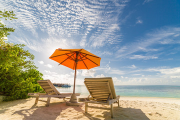 Beach scene. White sand, sun beds and umbrella and blue sky and blue sea