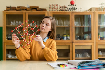 Female student holding molecular structure model. Science class concept.