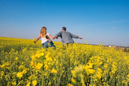 Romantic couple, with open arms, is running through the field