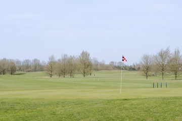 Obraz premium A red and white checkered golf course flagstick on a putting green.