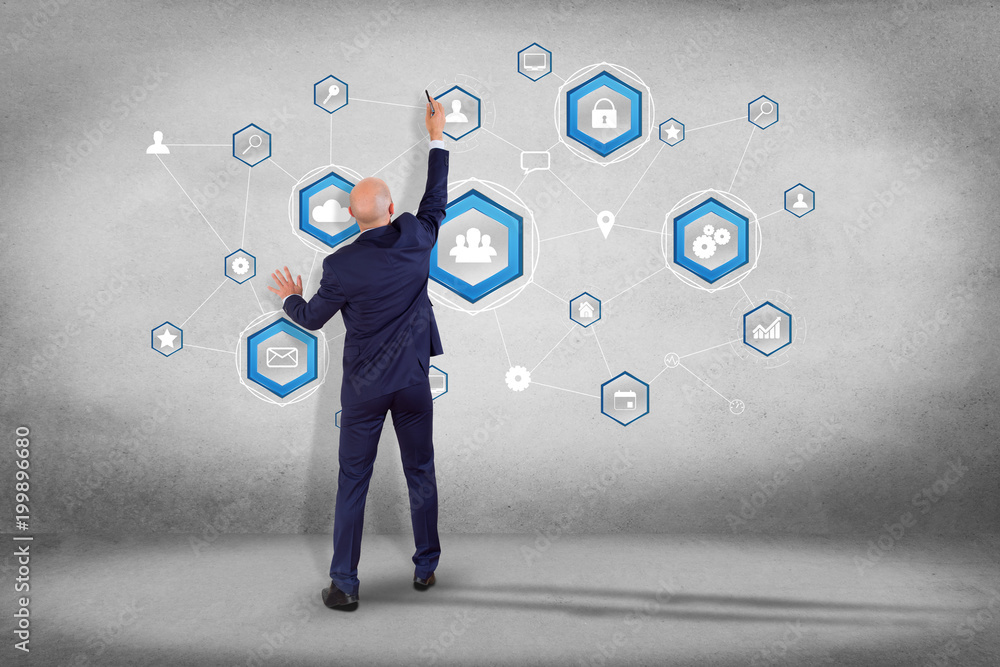 Poster businessman in front of a wall with a business network connection displayed on a futuristic interfac