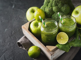 Green smoothie with ingredients, apples, lime, broccoli and spinach in box.