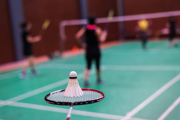 hand holding badminton racket and shuttlecock in badminton court