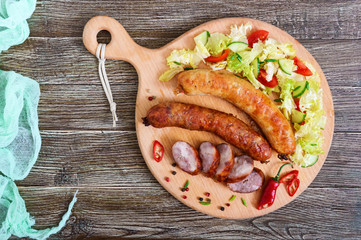 Juicy home made sausage with a light spring salad of fresh vegetables on a wooden tray on the table. A traditional Easter dish. Top view.