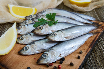 A small salted hamsa (sprat) with spices, lemon on a wooden background.