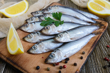 A small salted hamsa (sprat) with spices, lemon on a wooden background.