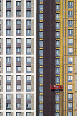 Worker at height in a red construction cradle