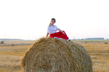 Naklejka na ściany i meble Lovely girl in a traditional costume walks on the field of cereals 