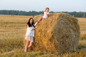 Naklejka na ściany i meble Mom and daughter walking in the grain fields