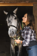 Fototapeta premium girl in plaid shirt with a horse in a stable