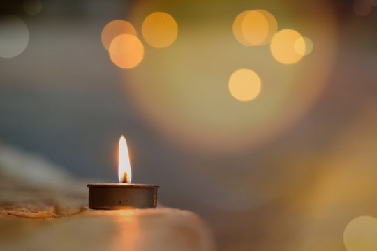 Prayer and hope concept.Candle flame light at night with abstract circular bokeh background