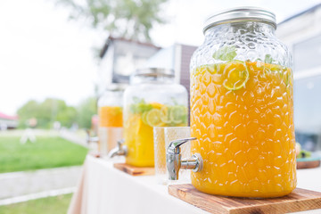 Glass bank of lemonade with sliced citrus fruits on a buffet table. Summer party outdoor. Detox.