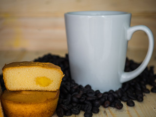 Roasted coffee seed and white cup on wooden background.