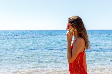 young smiling woman talking by phone on a beach