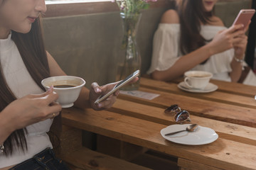 Obraz na płótnie Canvas Two teenage women meet in coffee shop use smartphone play social media together in afternoon, life style of new teenager