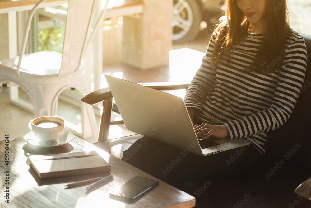 Wall mural beautiful young teenage woman freelance work with laptop at coffee shop in with sun light, freelance