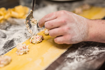 Chef's hands prepares Italian food stuffed pasta ravioli