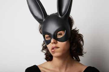 Close up portrait of attractive young and beautiful woman posing in lingerie and black bunny mask on white background
