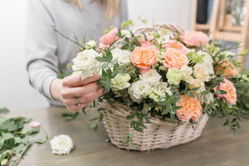 close-up hands female florist. Floral workshop - woman making a beautiful flower composition a bouquet in a wicker basket. Floristry concept