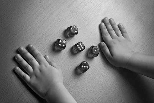 hands near dices on a board. Black white