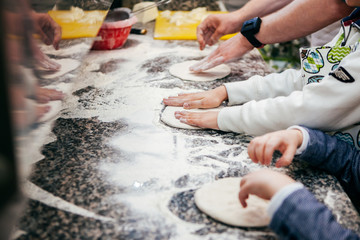 cook helps children prepare dough in the kitchen