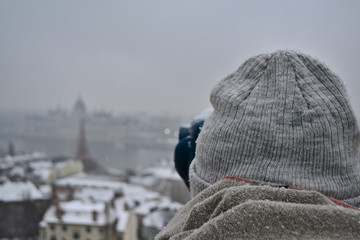 Girl is watching the city of Budapest, Hungary by binoculars in the winter