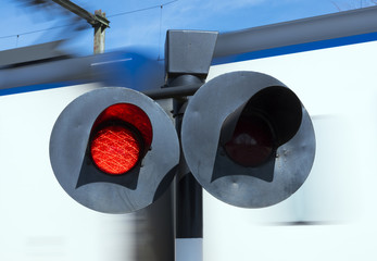flashing red lights while white train passes railway crossing