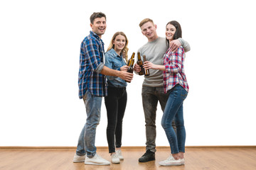 The four happy friends hold bottles of beer on a white wall background