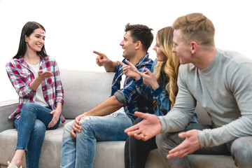 The four happy people on the sofa play the game on the white background