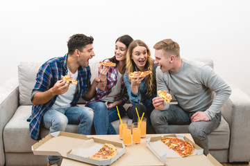 The four happy people on the sofa eat pizza on the white background