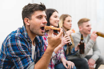 The four people on the sofa eat pizza and drink a beer on the white background