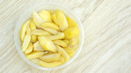 Thai pickled mangoes in a bowl on a wooden table.