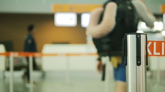 Close up of opening of fence pole with orange waiting line rope for registration for boarding the airplane. Backpacker going chek in for travel by plane.