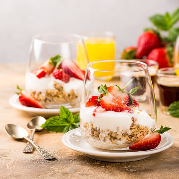 Healthy breakfast with oatmeal granola, strawberries and yogurt on light brown background. Copy space.