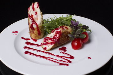On a white plate, meat in breadcrumbs of sesame, arugula, tomato, basil and ketchup.Tasty and beautiful food. Cherry tomatoes.