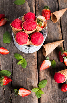 Ice cream. Strawberry ice cream scoop in waffle cone on wooden concept.