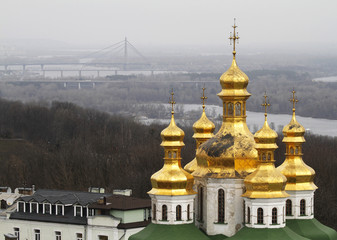 Fototapeta na wymiar Golden domes of the Church of All Saints in Pechersk Lavra i Kiev, Ukraine. On the background the Pivnichnyi Bridge which crosses Dnieper River.