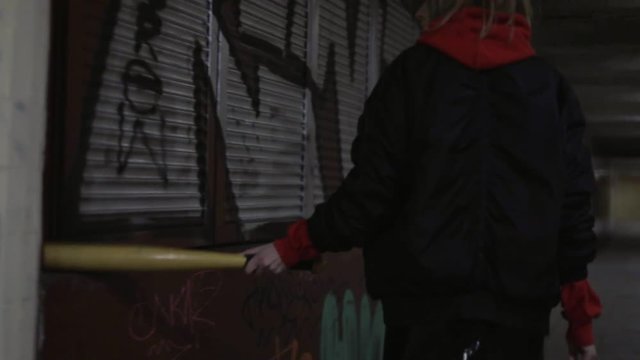 Sporty swag girl with baseball bat is walking in tunnel