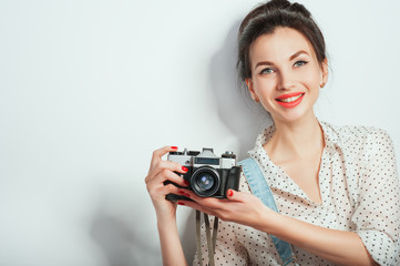Fashion look, pretty cool young woman model with retro camera wearing in denim clothes posing on white wall. Expressive beauty girl photographer holding photocam. Emotions Lifestyle People concepts