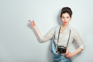 Fashion look, pretty cool young woman model with retro camera wearing in denim clothes pointing on copy space. Expressive beauty girl photographer holding photocam. Emotions Lifestyle People concepts