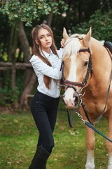 Foto op Canvas portrait beautiful young girl in white shirt and black pants with beauty long hair next horse in forest. Fashionable elegance woman posing near animal. Beauty Lifestyle Fashion People Animals concepts © victoriazarubina