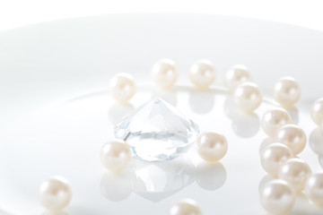 Luxury concept.  White pearl and one diamond in a plate