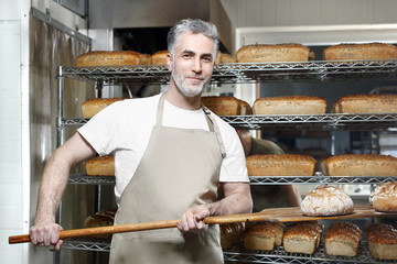 Piekarz w piekarni. Smakowity świeży chleb prosto z pieca. - obrazy, fototapety, plakaty