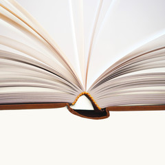 Fragment of open book, hardback, white sheets on white and grey background. Education background. Back to school. Copy space for text. Close-up, selective focus