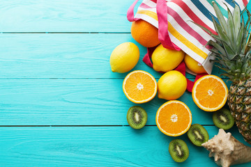 Citrus fresh food. Summer holidays. Orange, kiwi, pineapple, lemon and sea shell on blue wooden background. Vacation and summertime.Top view and copy space. Mock up
